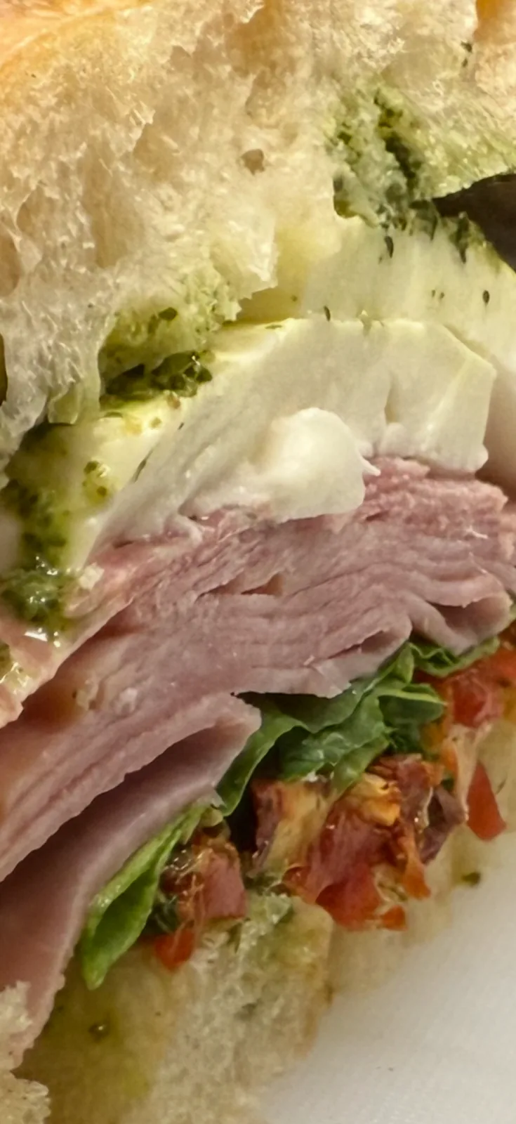 An artisan sandwich layered with fresh greens, tomato, cheese, and sliced turkey